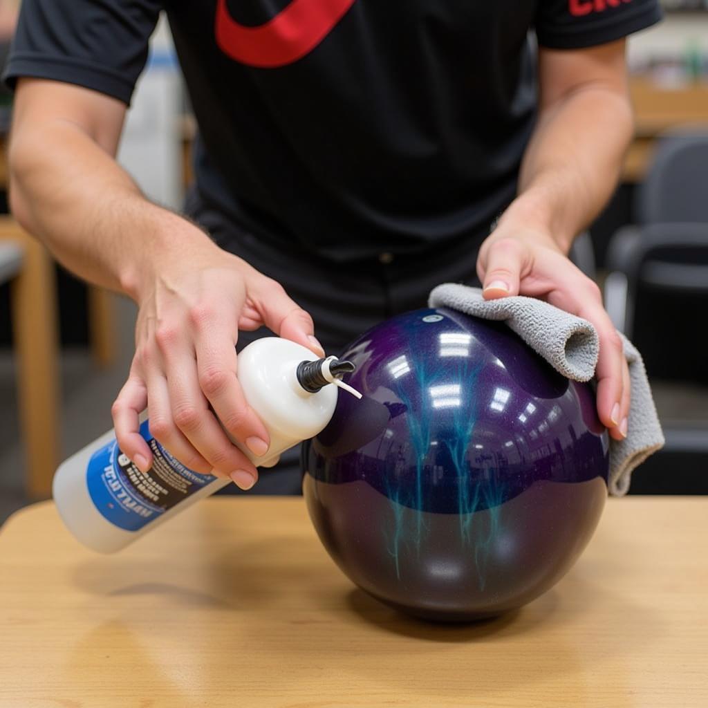 A bowler cleaning their crystal bowling ball with a specialized cleaner.